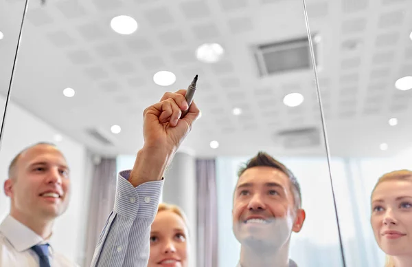 Man with marker writing on glass wall at office — Stock Photo, Image