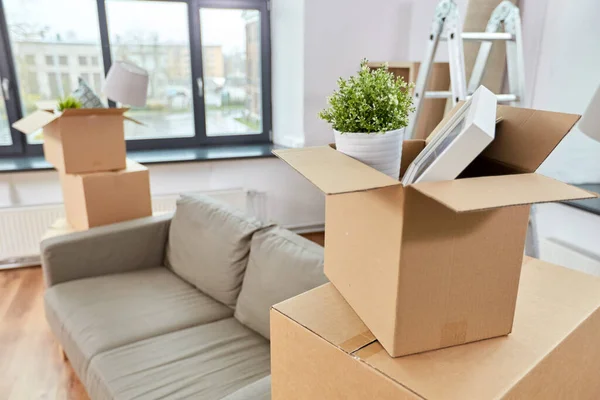 Sofá y cajas acanaladas con cosas en casa nueva —  Fotos de Stock