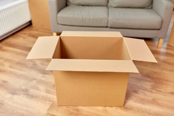 Caja de cartón corrugado vacío y sofá en el nuevo hogar —  Fotos de Stock