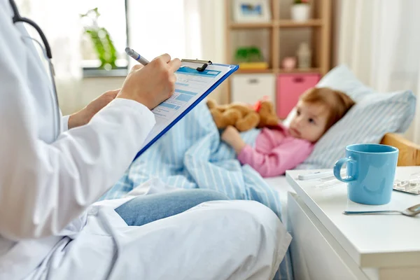 Médico con portapapeles y chica enferma en la cama en casa — Foto de Stock