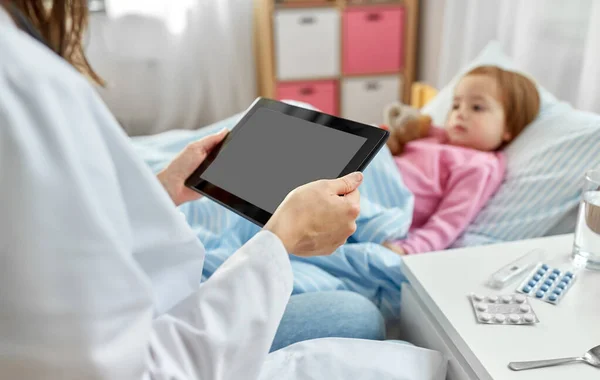 Médico com computador tablet e menina doente na cama — Fotografia de Stock