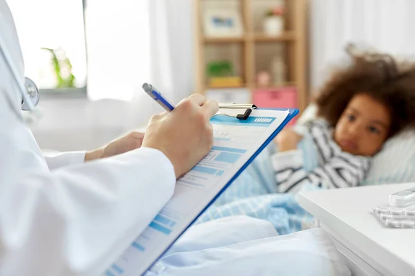 Médecin avec presse-papiers et fille malade au lit à la maison — Photo