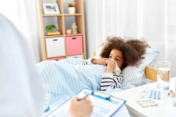 Médico con portapapeles y chica enferma en la cama en casa — Foto de Stock