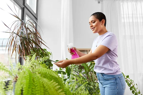 Femeie pulverizând planta de casă cu apă acasă — Fotografie, imagine de stoc