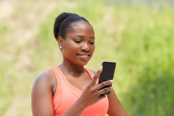 Sportovní africký žena pomocí smartphone venku — Stock fotografie
