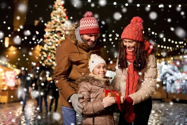 Happy family with gift at christmas market in city — Stock Photo, Image