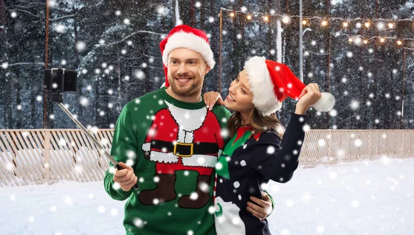 Happy couple in christmas sweaters taking selfie — Stock Photo, Image