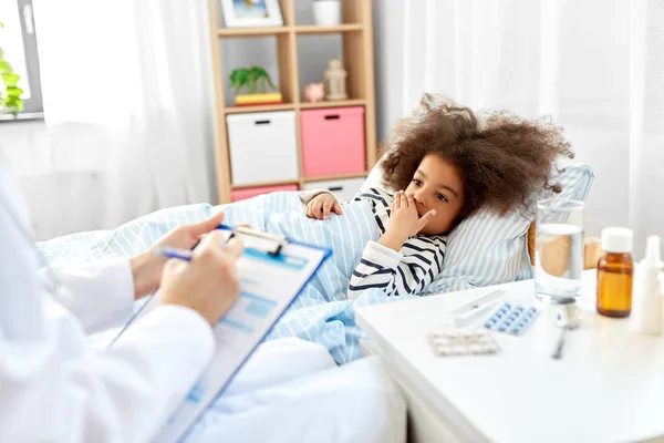 Médico com prancheta e menina doente na cama em casa — Fotografia de Stock