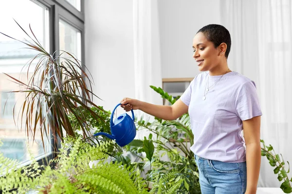 African american woman watering plants at home — Stock Photo, Image