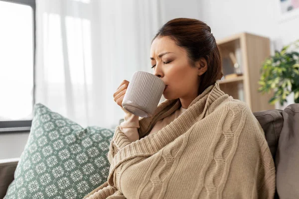 Sick asian woman drinking hot tea at home — Stock Photo, Image