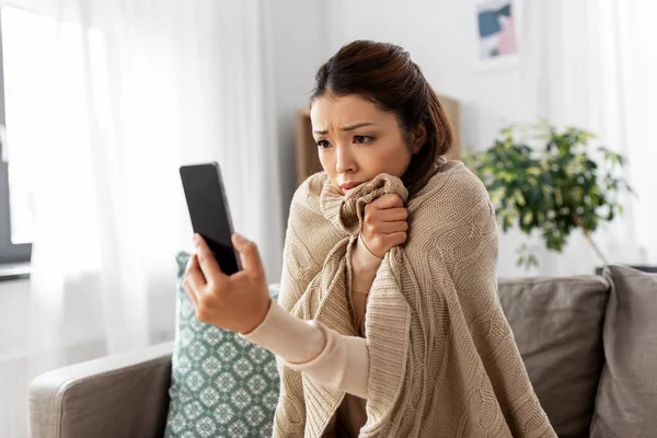 Θλιβερή άρρωστη γυναίκα σε κουβέρτα χρησιμοποιώντας smartphone στο σπίτι — Φωτογραφία Αρχείου