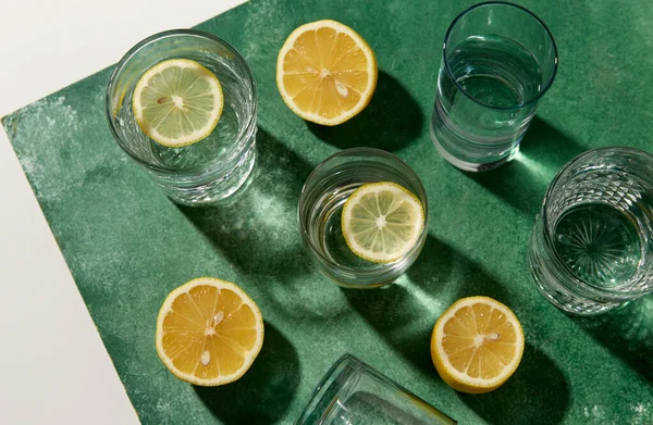 緑の背景に水とレモンの入ったメガネは — ストック写真