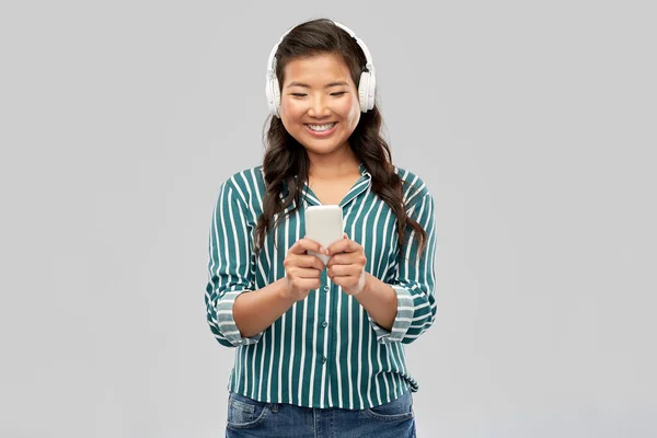 Feliz asiático mujer en auriculares escuchando música — Foto de Stock