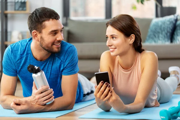 Feliz pareja con smartphone después de los deportes en casa —  Fotos de Stock