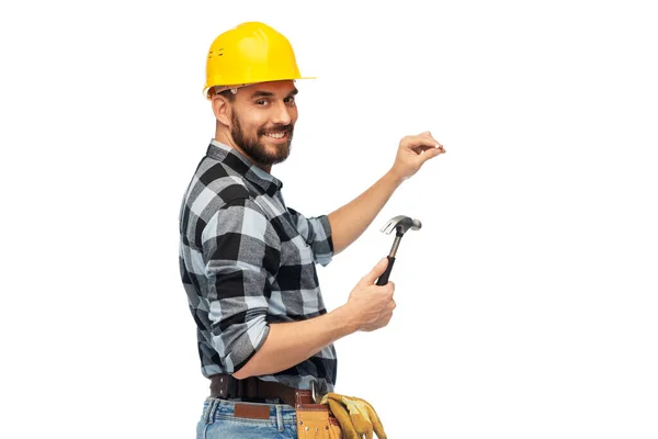 Happy male builder in helmet with hammer and nail — ストック写真