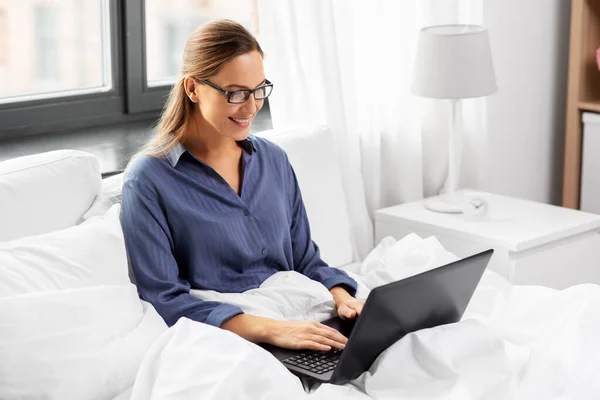 Jeune femme avec ordinateur portable dans le lit à la maison chambre — Photo