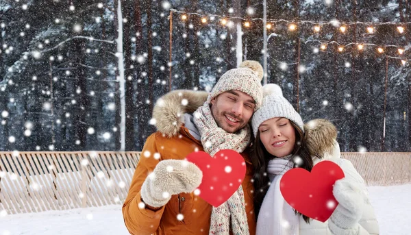 Szczęśliwa para z czerwonymi sercami na lodowisku w zimie — Zdjęcie stockowe