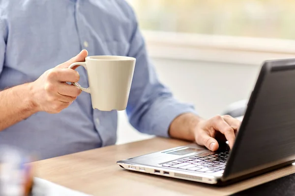 Bilgisayarlı bir adam ev ofisinde kahve içiyor. — Stok fotoğraf