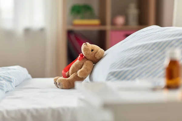 Игрушка плюшевый медведь в постели и лекарства на дому — стоковое фото