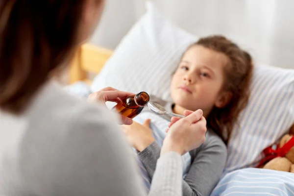 Mother pouring cough syrup for sick daughter — Stock Photo, Image