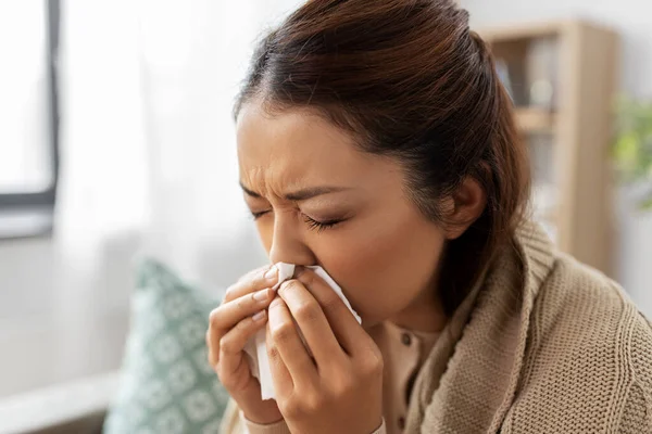 Sick woman blowing nose in paper tissue at home — Stock Photo, Image