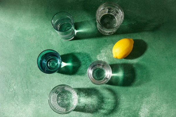 Verres avec de l'eau et des citrons sur fond vert — Photo