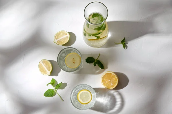 Bicchieri con acqua al limone e menta piperita in tavola — Foto Stock