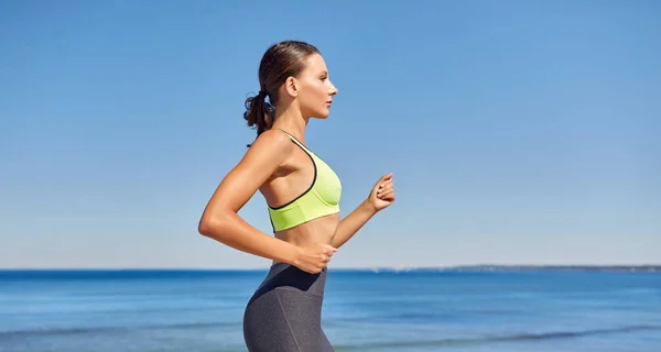 Young woman running along sea promenade — Stock Photo, Image