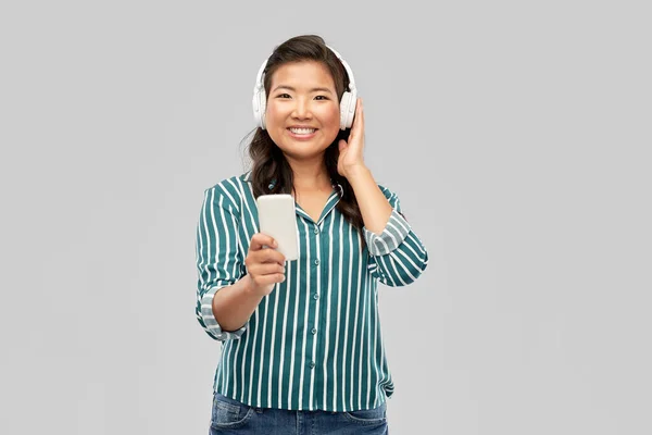 Glad asiatisk kvinna i hörlurar lyssnar på musik — Stockfoto