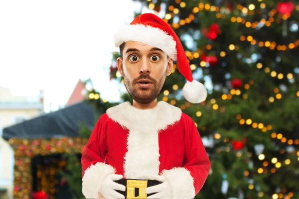 Překvapený muž v santa kostým přes vánoční strom — Stock fotografie