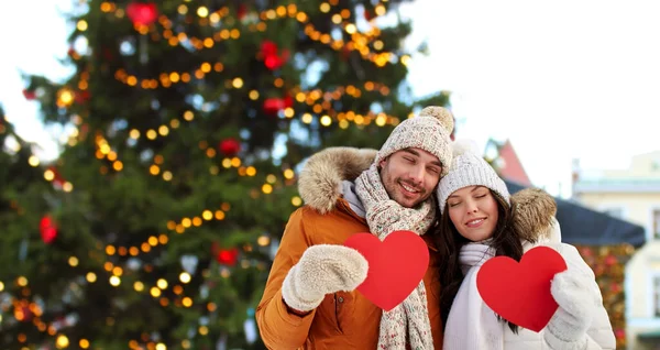 Счастливая пара с красными сердцами на рождественском рынке — стоковое фото