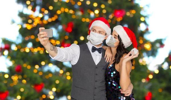 Casal em máscaras médicas tomando selfie no Natal — Fotografia de Stock