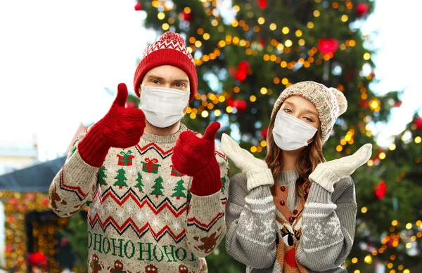 Casal em máscaras protetoras e blusas de Natal — Fotografia de Stock