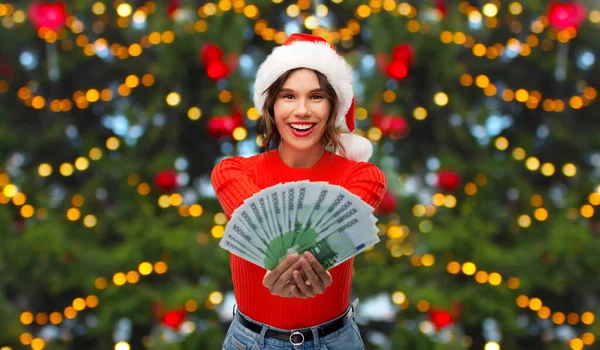 Gelukkig vrouw in santa hoed met geld op kerst — Stockfoto