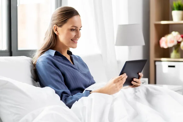 Young woman with tablet pc in bed at home bedroom — Stock Photo, Image