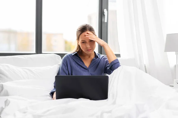 Jovem estressado com laptop na cama em casa — Fotografia de Stock