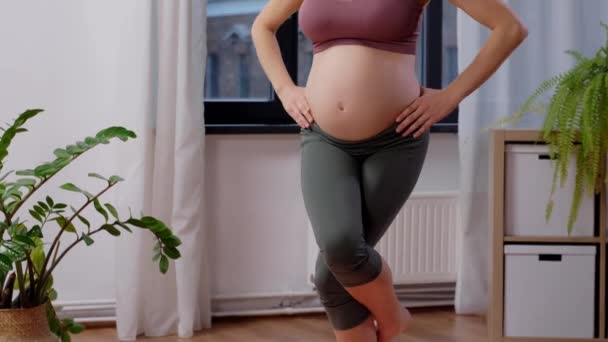 Счастливая беременная женщина занимается йогой дома — стоковое видео