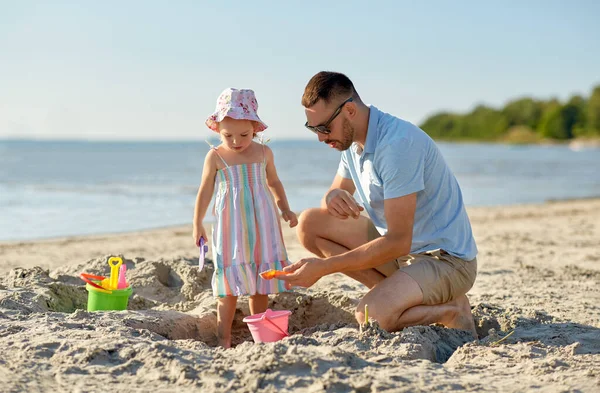 Far og datter som leker med leker på stranda – stockfoto