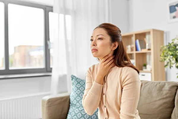 Doente mulher asiática tocando sua dor de garganta em casa — Fotografia de Stock
