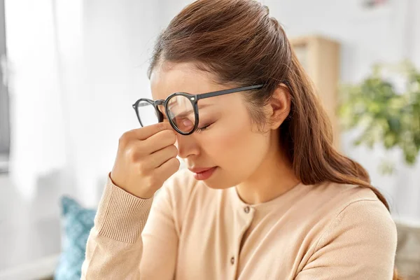 Müde asiatische Frau mit Brille reibt Nasenbrücke — Stockfoto