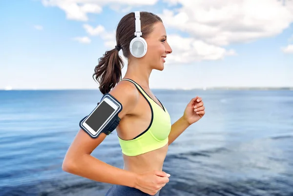 Mujer corriendo en auriculares con teléfono inteligente — Foto de Stock