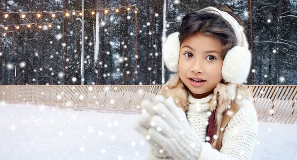 Menina em earmuffs no ringue de patinação no gelo no inverno — Fotografia de Stock