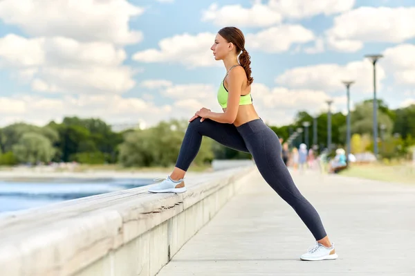 Spor yapan ve bacak esneten mutlu genç bir kadın. — Stok fotoğraf