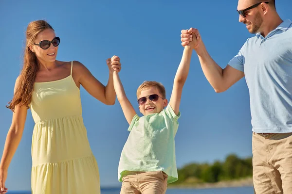 Familia feliz caminando a lo largo de la playa de verano — Foto de Stock