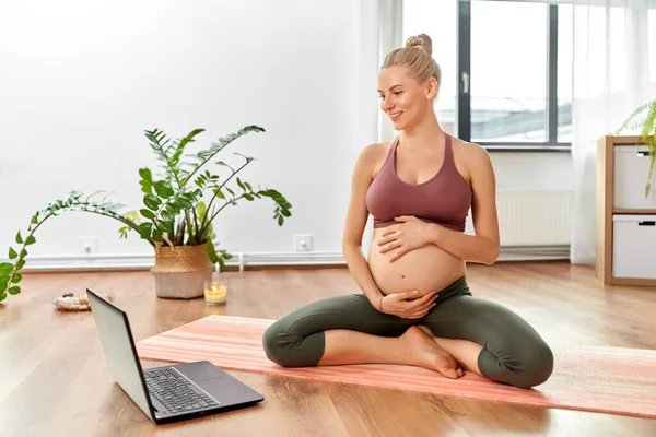 Pregnant woman with laptop doing yoga at home — Stock Photo, Image