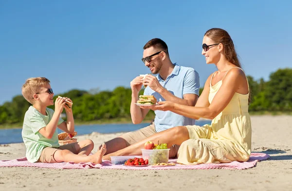 Familia feliz teniendo picnic en la playa de verano —  Fotos de Stock