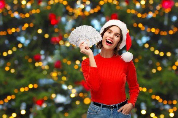 Lycklig kvinna i tomte hatt med pengar på jul — Stockfoto