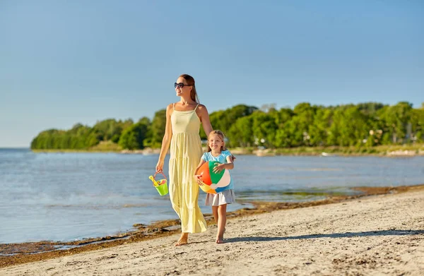 Mãe e filha com bola andando ao longo da praia — Fotografia de Stock