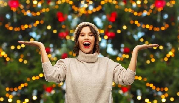 Happy woman holding something over christmas tree — Stock Photo, Image