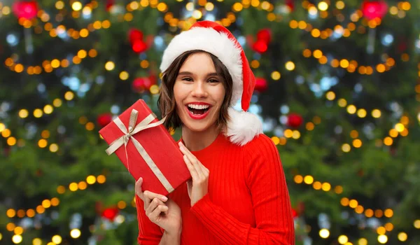 Felice giovane donna in cappello di Babbo Natale con scatola regalo rossa — Foto Stock